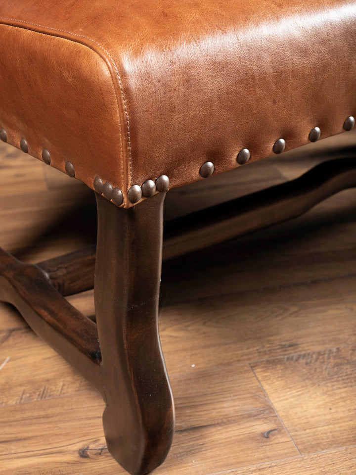 Detailed view of the Longhorn Leather Bench showcasing full-grain buffalo leather, handcrafted hardwood legs, and individually applied brass nailhead trim.