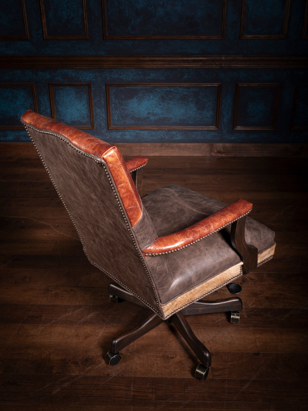 Side and back view of the longhorn leather desk chair with distressed brown leather, nailhead trim, and a comfortable padded seat, mounted on a swivel base with wheels.