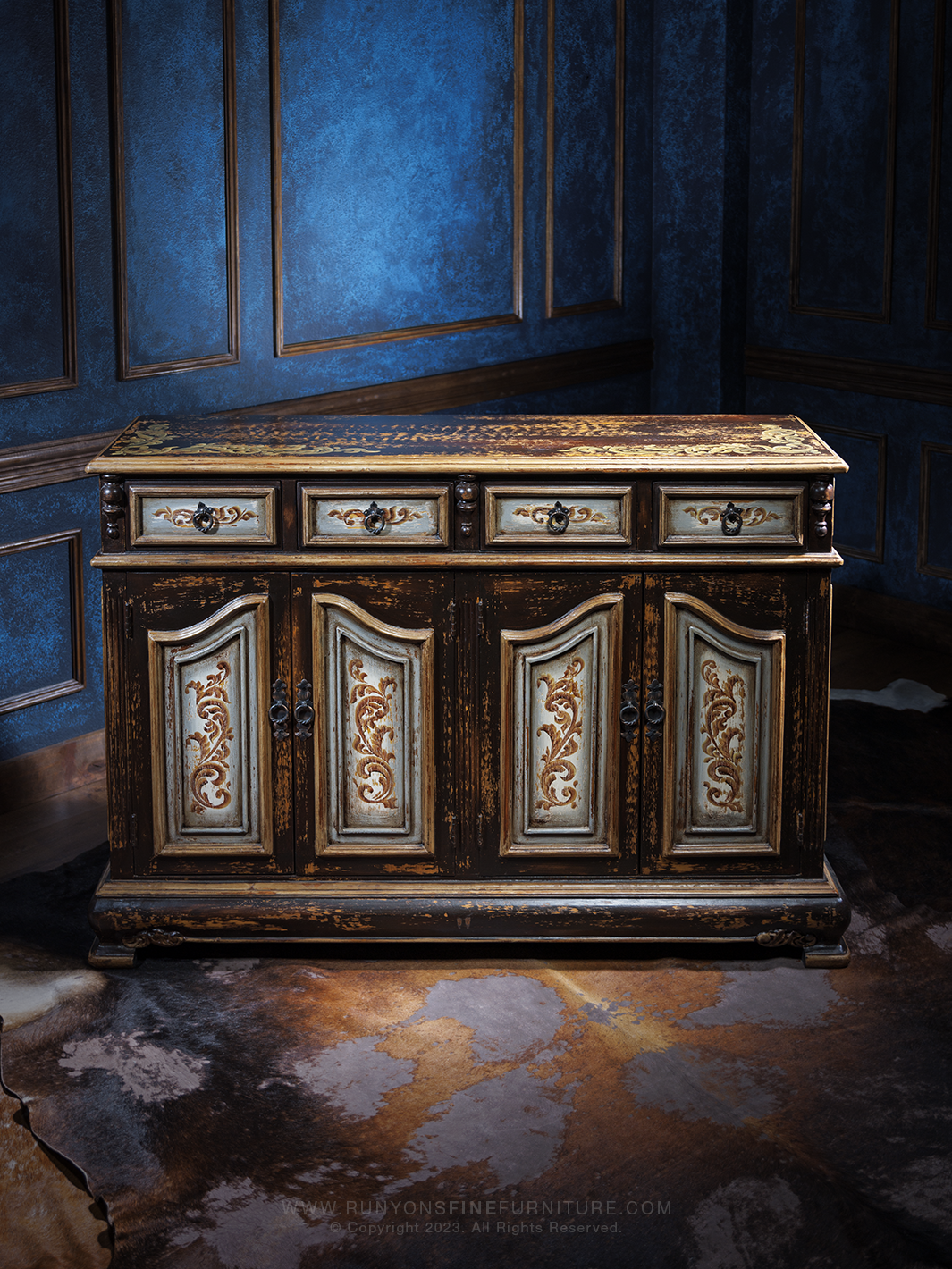 Front downward angle view of an Old World-style buffet with a distressed finish, featuring ornate carved details on the doors and drawers, accented with antique-style hardware.