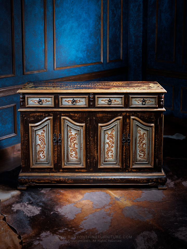 Front downward angle view of an Old World-style buffet with a distressed finish, featuring ornate carved details on the doors and drawers, accented with antique-style hardware.