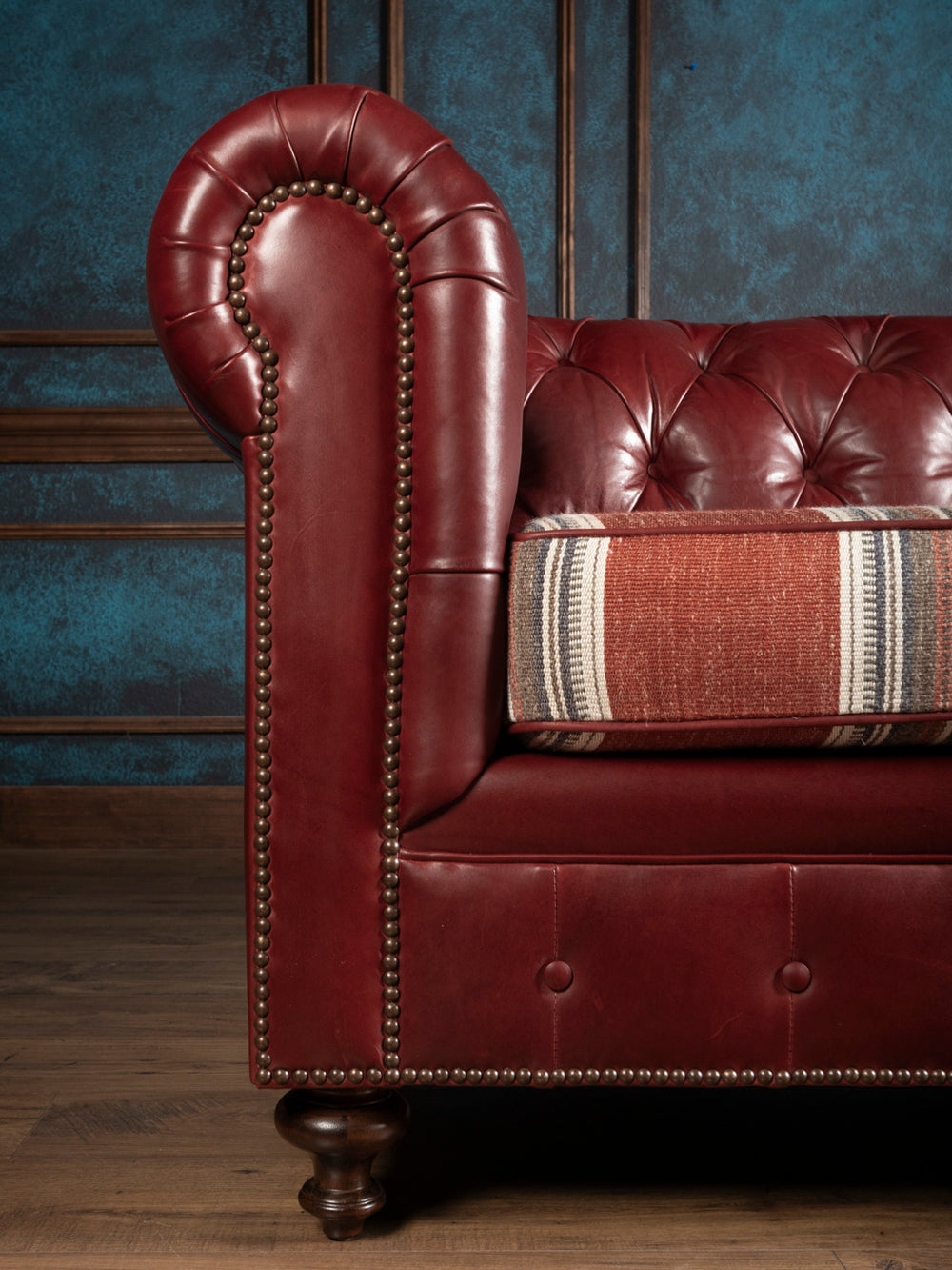 Close up front profile view of the rolled arm on the West Texas Estate leather Chesterfield sofa showing antique brass nailhead trim.