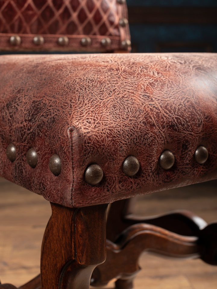 Distressed full-grain leather seat with burgundy-brown tones and decorative nailhead trim on the Prescott dining chair