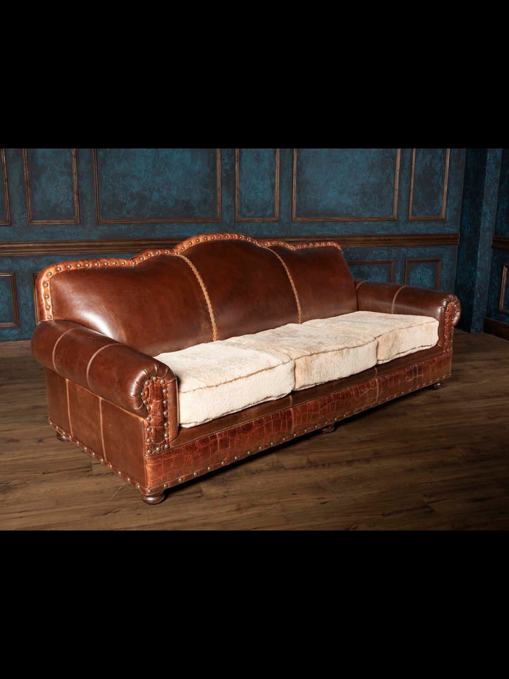 Three-quarter view of a luxury American Western ranch style sofa with full grain leather frame and cream shearling seats.