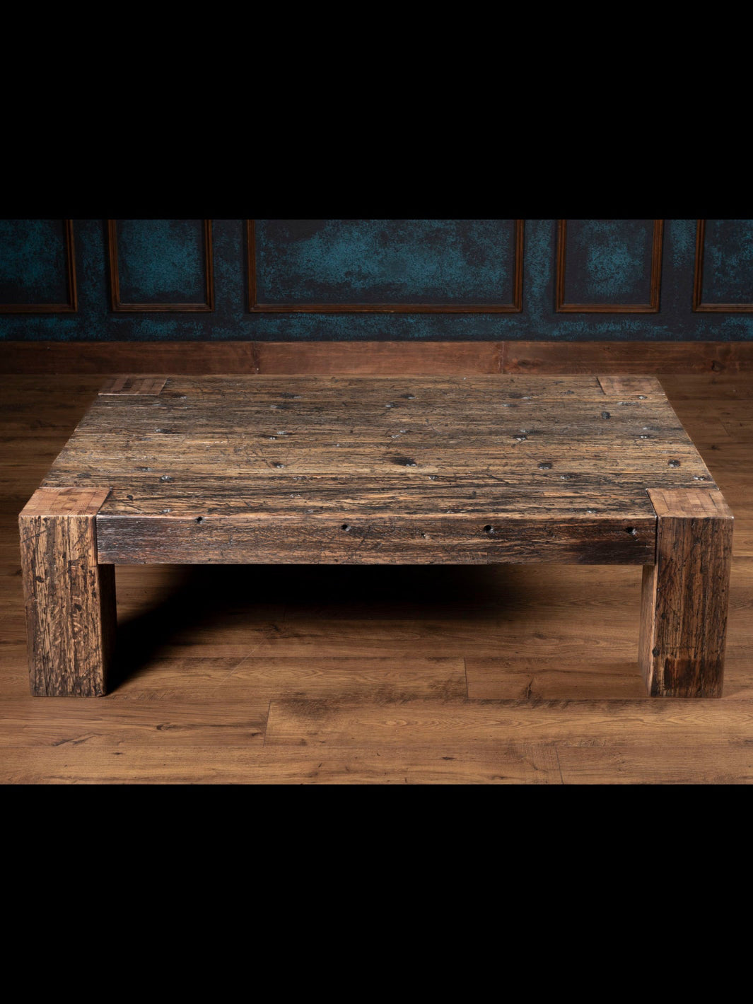 Reclaimed Oak Plank Coffee Table with distressed wood and thick plank legs in a rustic room. 
