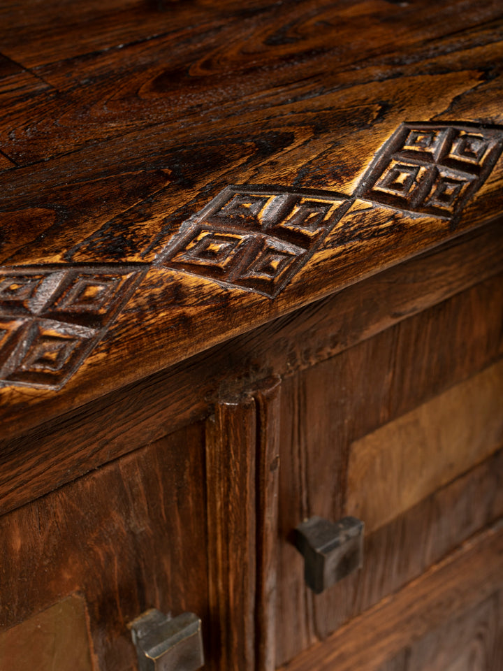 Macro perspective highlighting the textured grain of the reclaimed wood nightstand accented by artisanal hand carved diamond patterns.