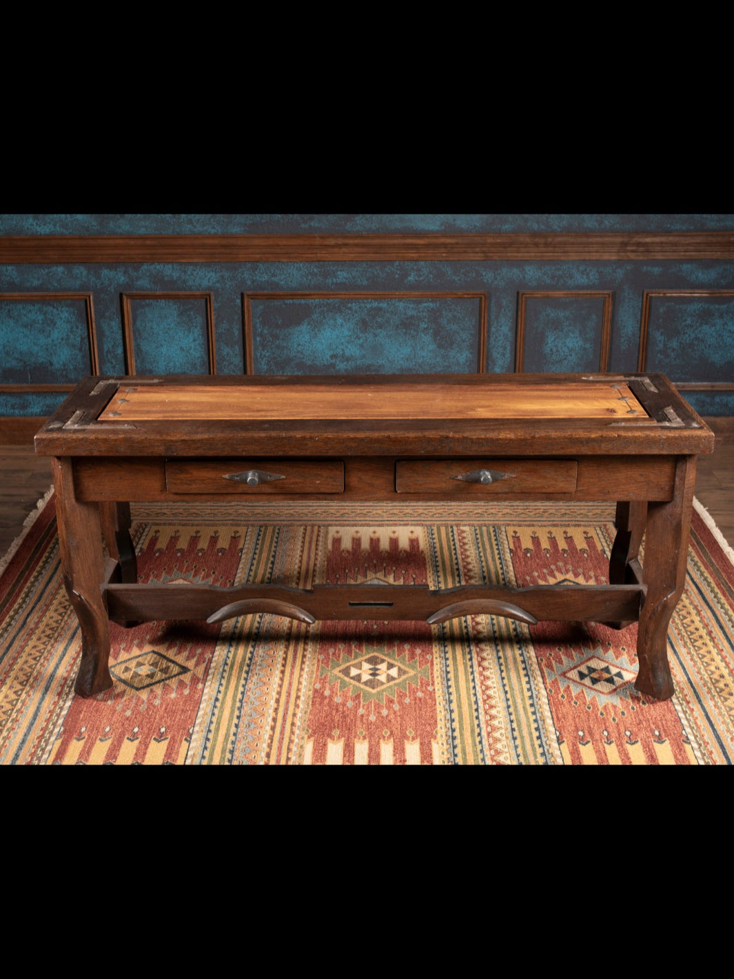 Wooden console with drawers in a room with patterned rug and decorative wall.