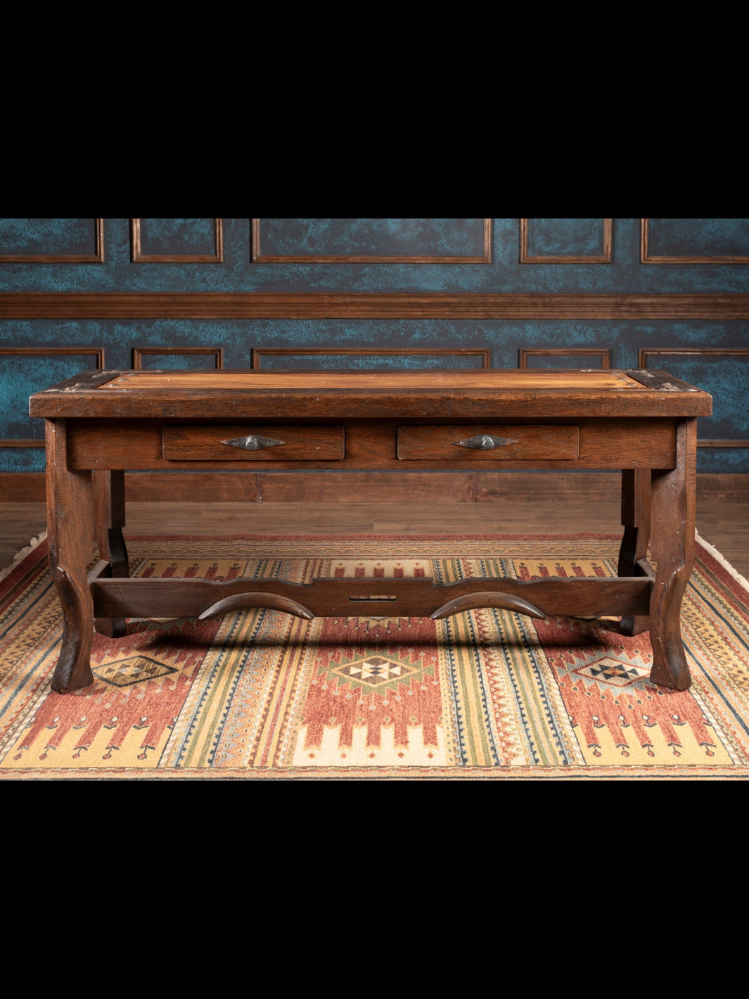 Wooden console with drawers in a room with patterned wallpaper and rug.