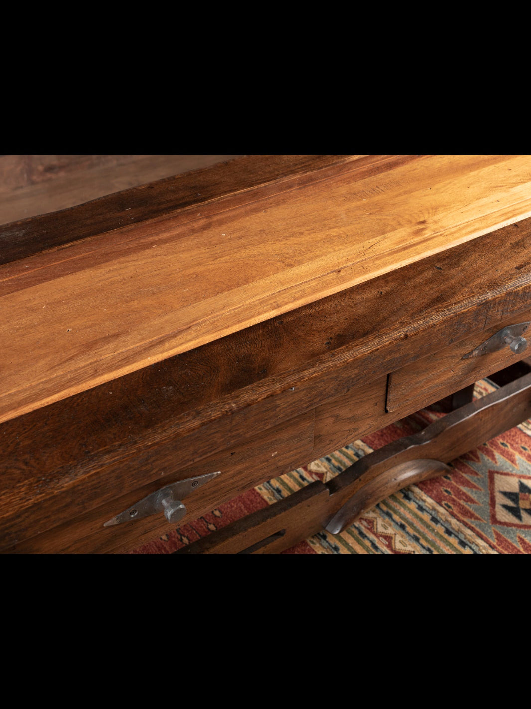Close-up of a wooden console with a textured surface and visible grain.