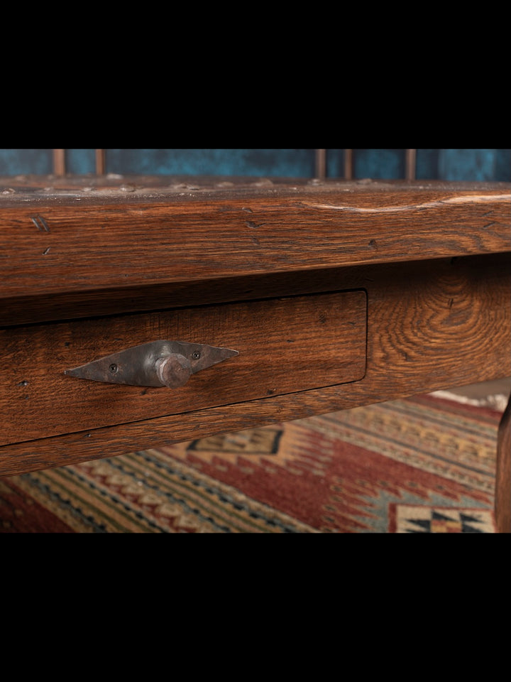 Close-up of a wooden drawer with a metal handle on a patterned rug.