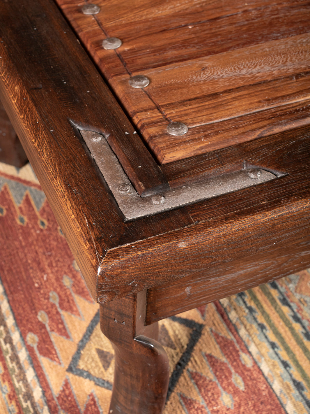 Close-up of a wooden coffee table with metal brackets on a patterned rug
