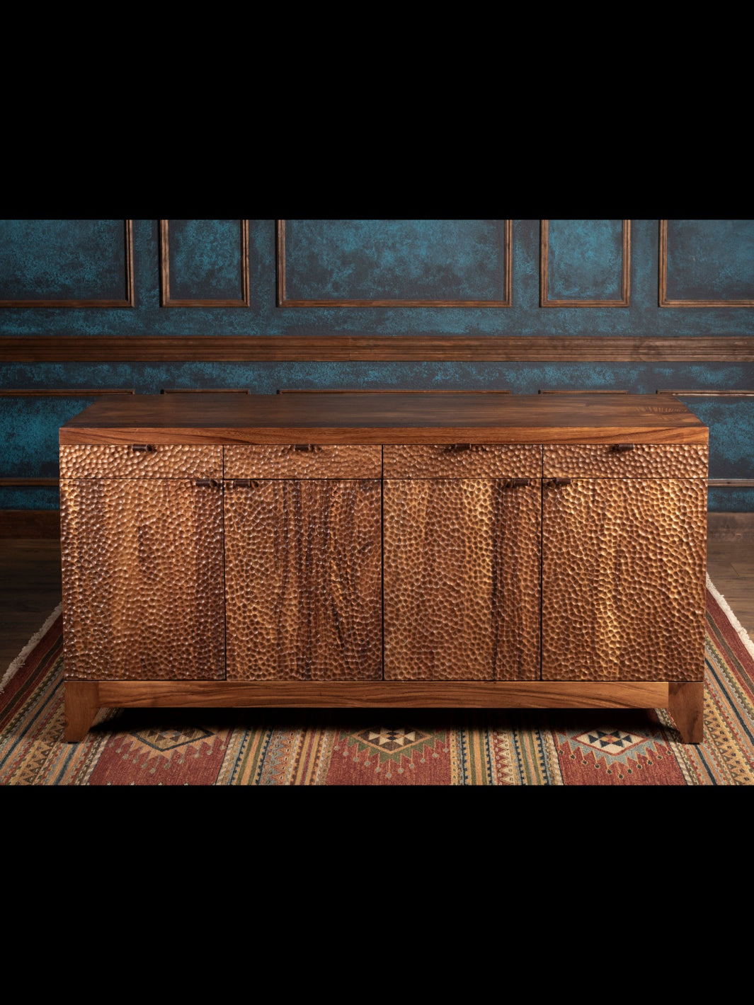 Wooden sideboard against a decorative wall with blue wallpaper