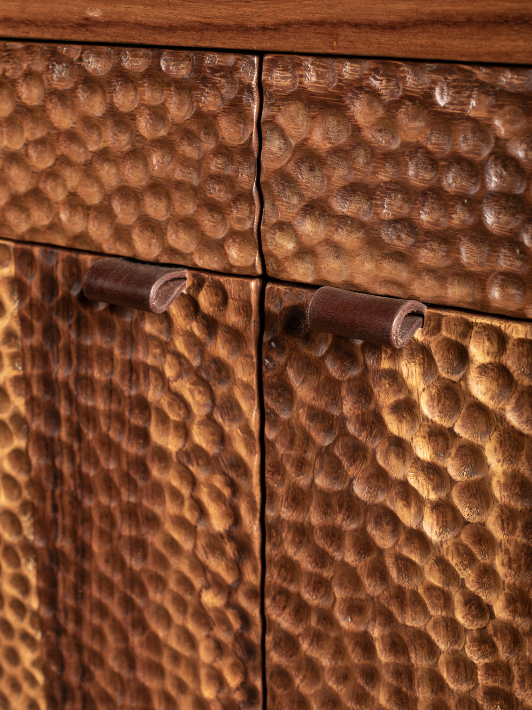 Close-up of a wooden cabinet with textured surface and metal handles.