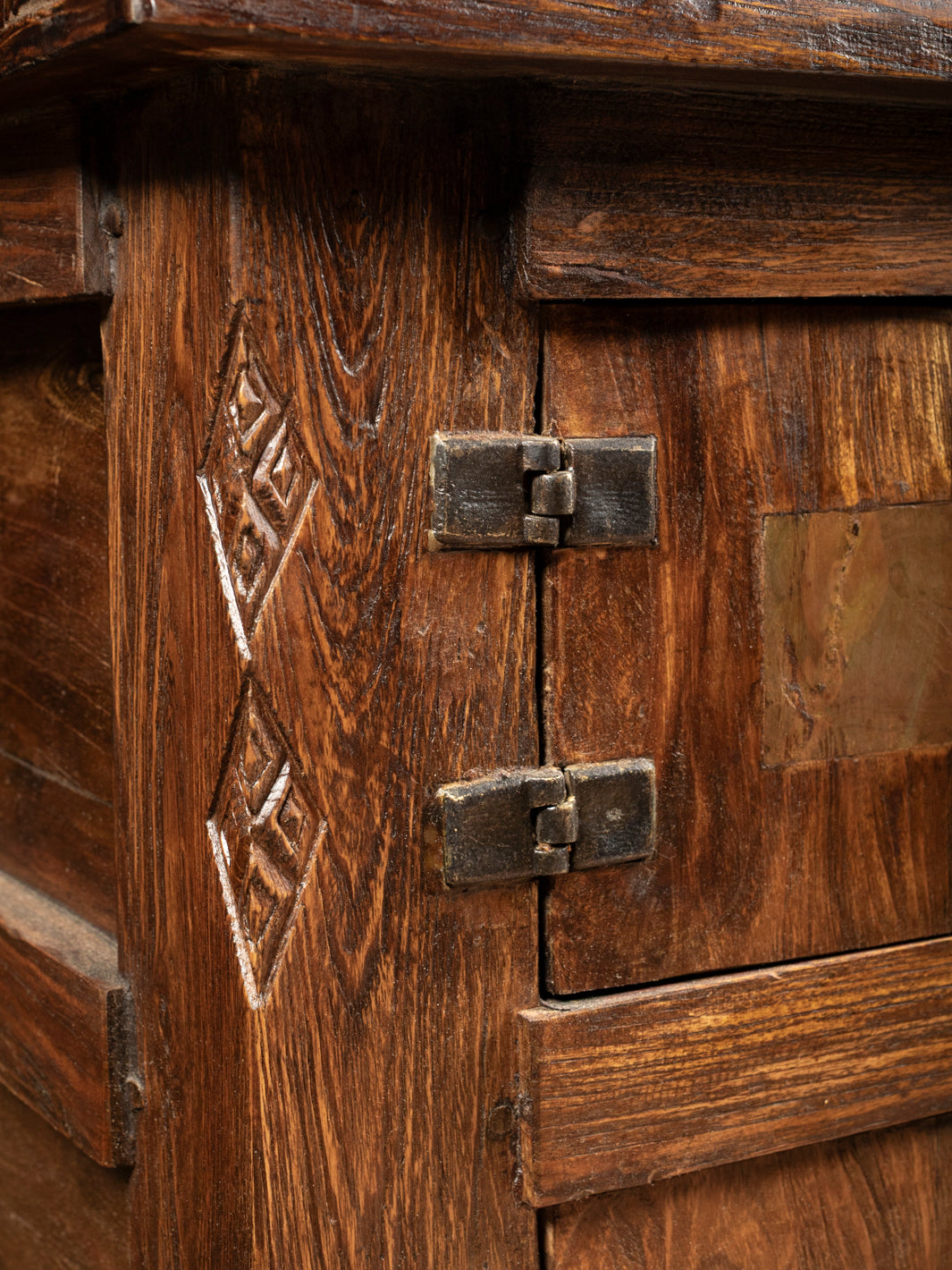 Extreme close up of the heavy duty rustic iron strap hinges mounted to the hand carved frame of the Jason Scott bedside chest.