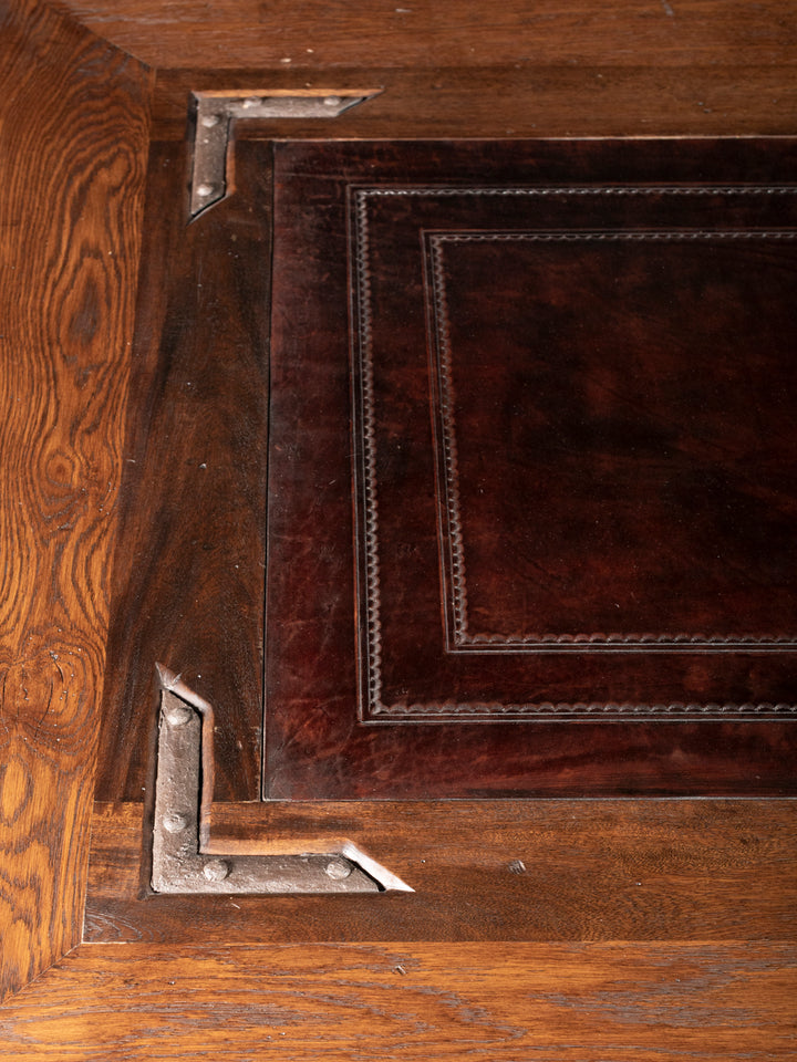 Nevada Cocktail Table with brown leather-inlay top framed by iron corner accents and distressed wood in a close-up view.