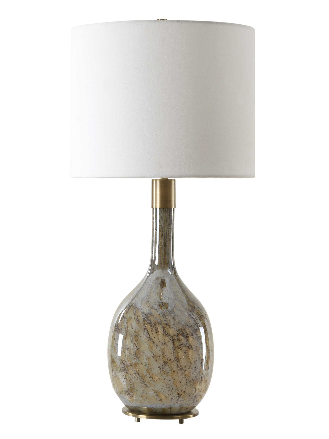 A decorative table lamp with a rounded glass base featuring swirling earthy tones of beige and brown, topped with a white fabric drum shade and a brass accent near the neck