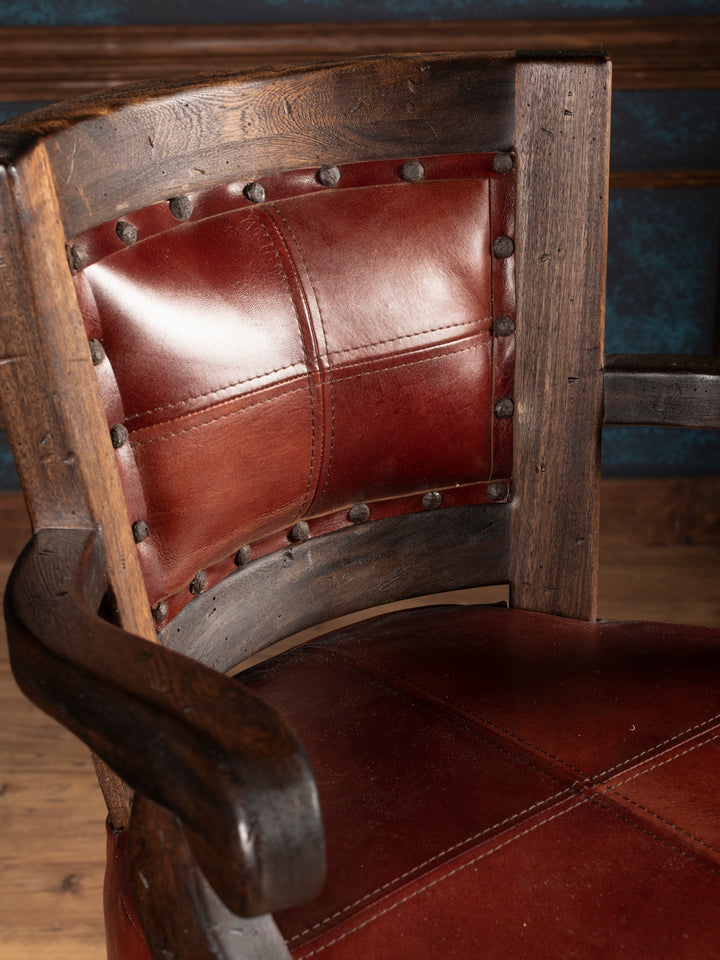 Close-up of a wooden bar stool with leather seat and backrest.