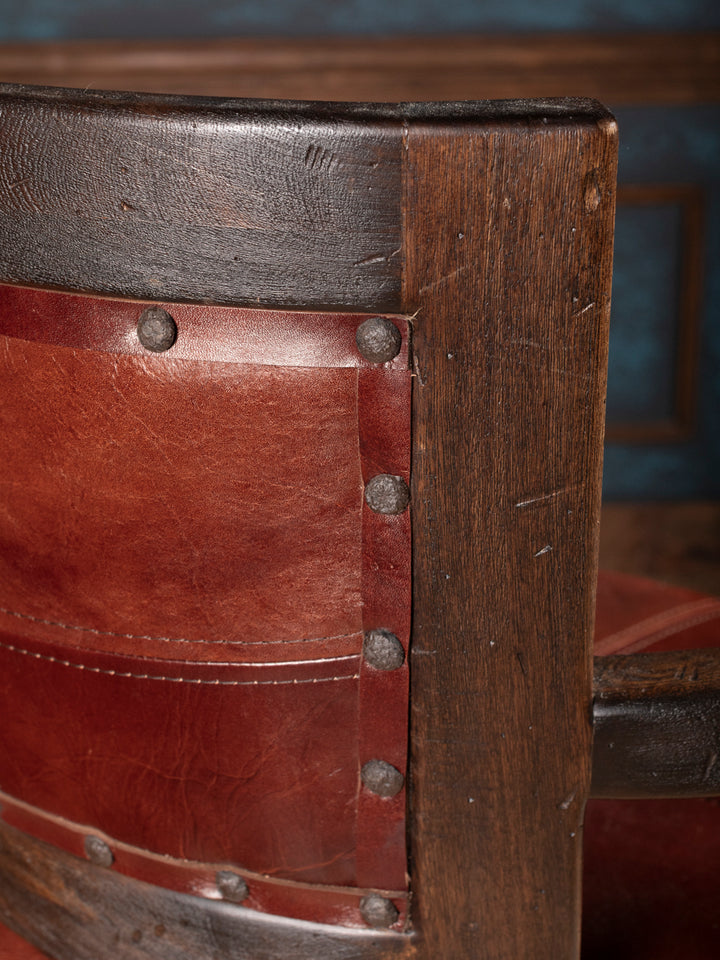 Close-up of a wooden bar stool with leather seat and metal rivets.