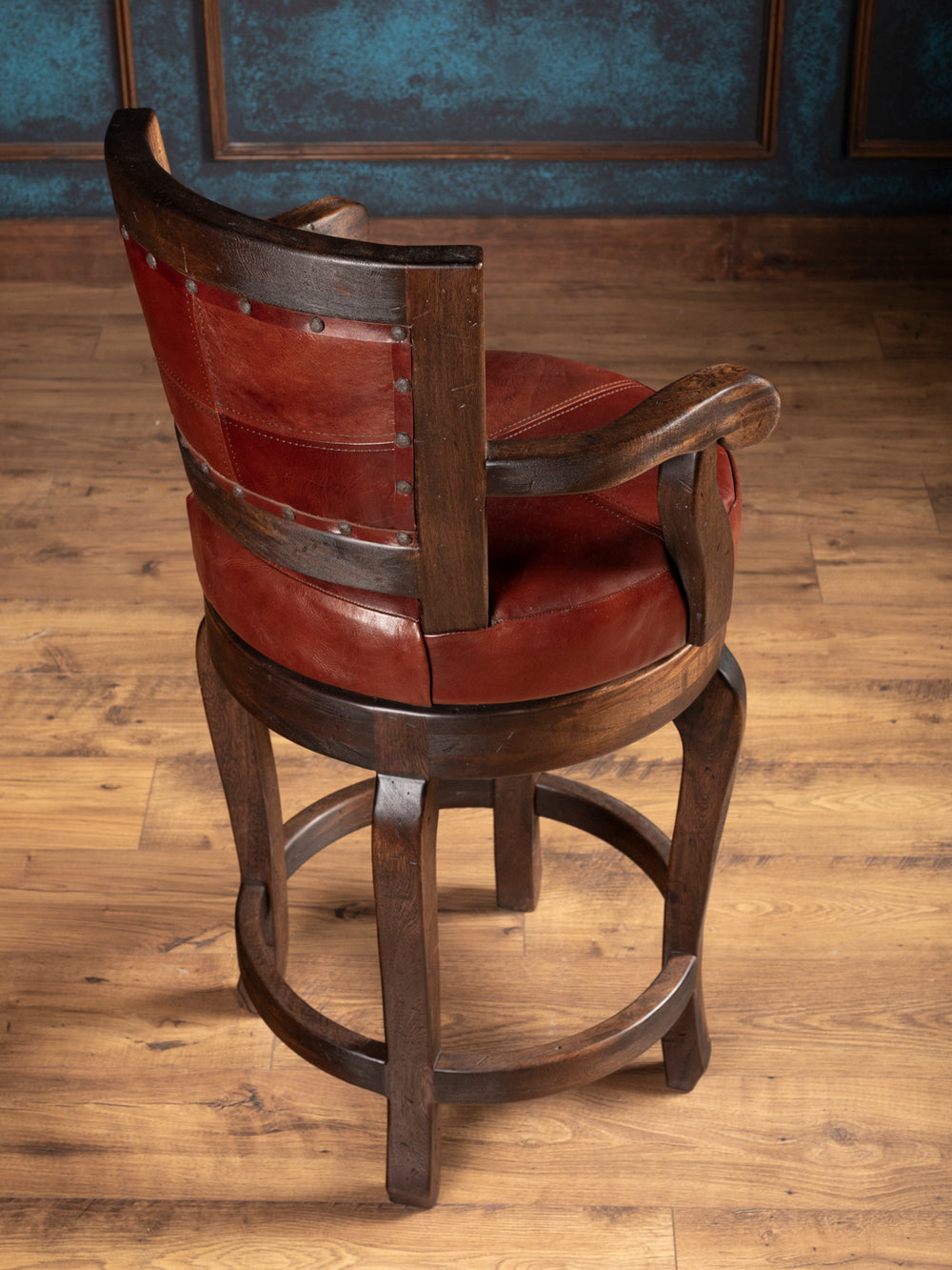 back view of wooden bar stool with red leather seat and backrest on a wooden floor.