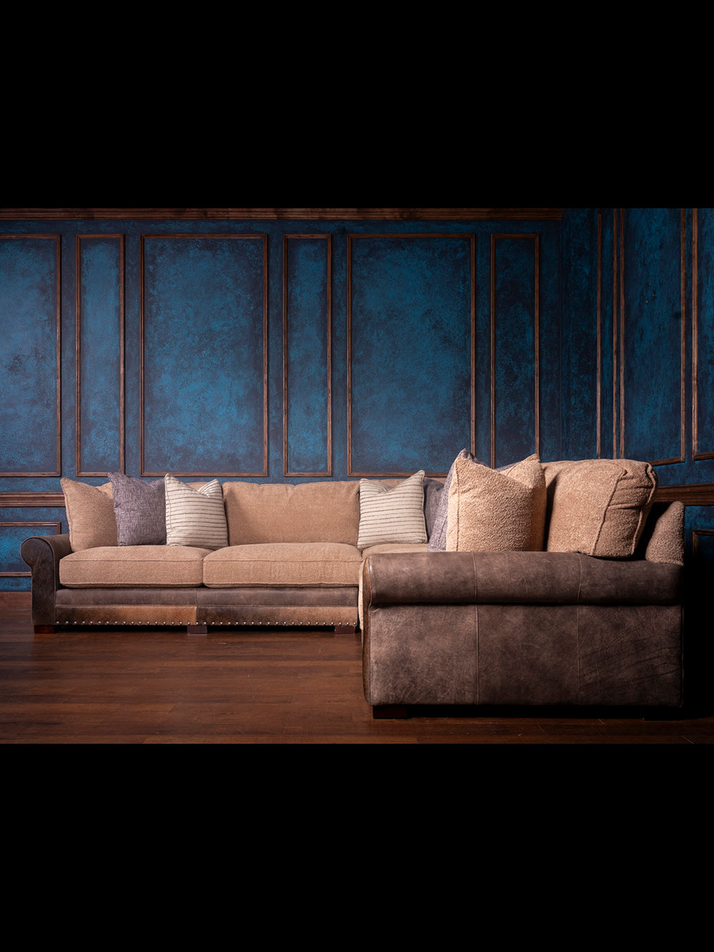 Sectional sofa with decorative pillows against a textured blue wall.