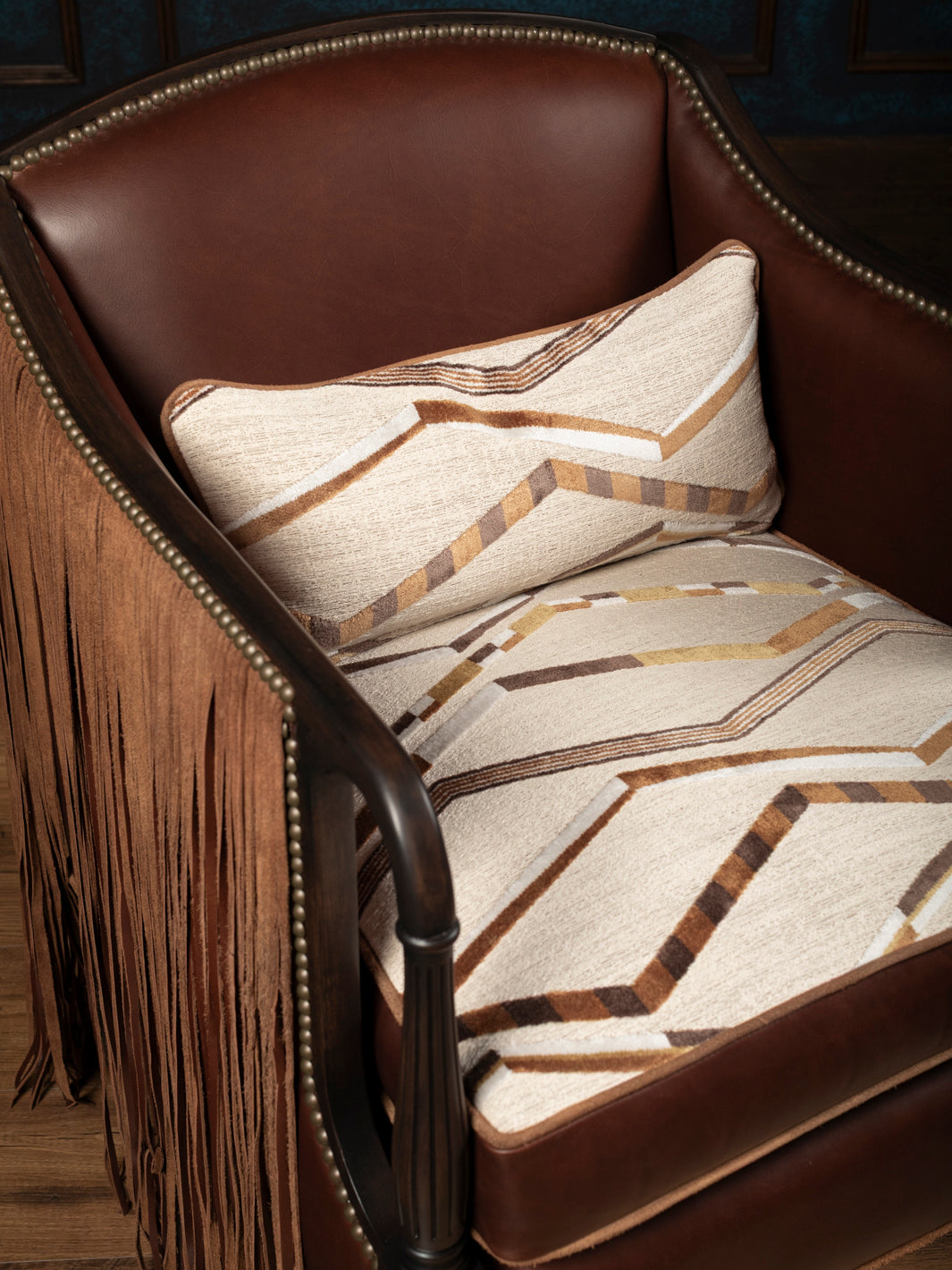 Detailed high-angle shot of the southwestern geometric fabric seat cushion on a premium cognac full-grain leather accent chair.
