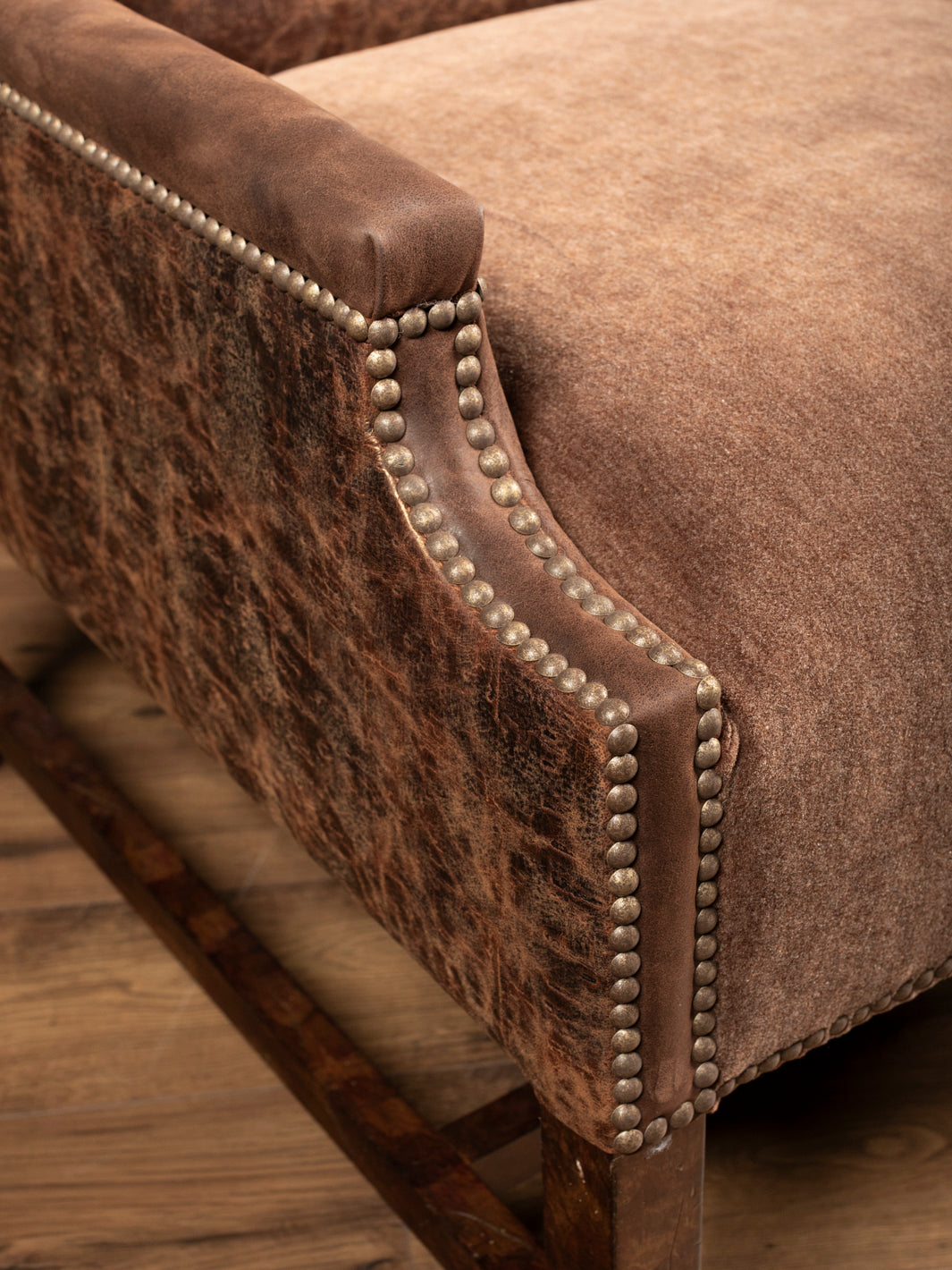 Close up of the Stockman Accent Chair with distressed leather accents and brass nailhead design on trim.