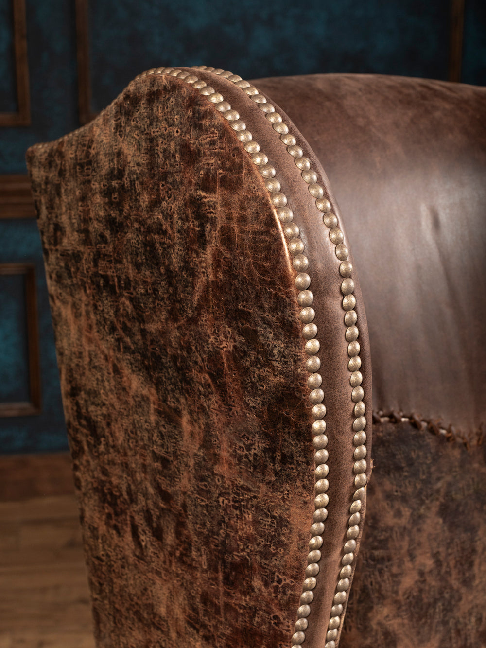 Close-up of distressed embossed leather and double rows of nailhead trim on the Stockman chair’s wing