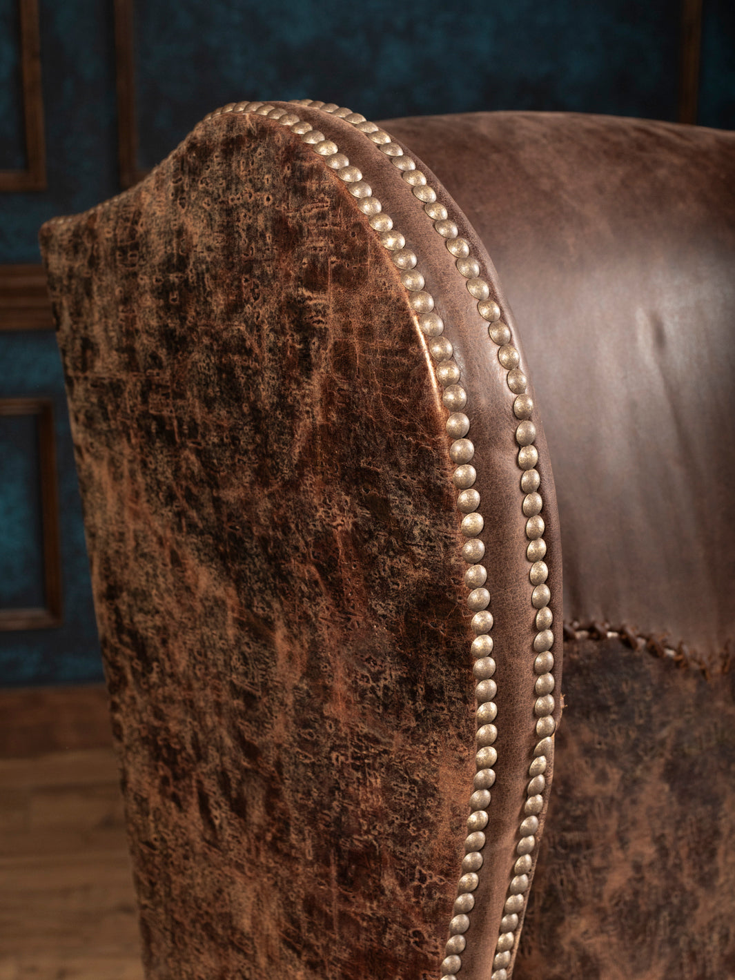 Close-up of distressed embossed leather and double rows of nailhead trim on the Stockman chair’s wing
