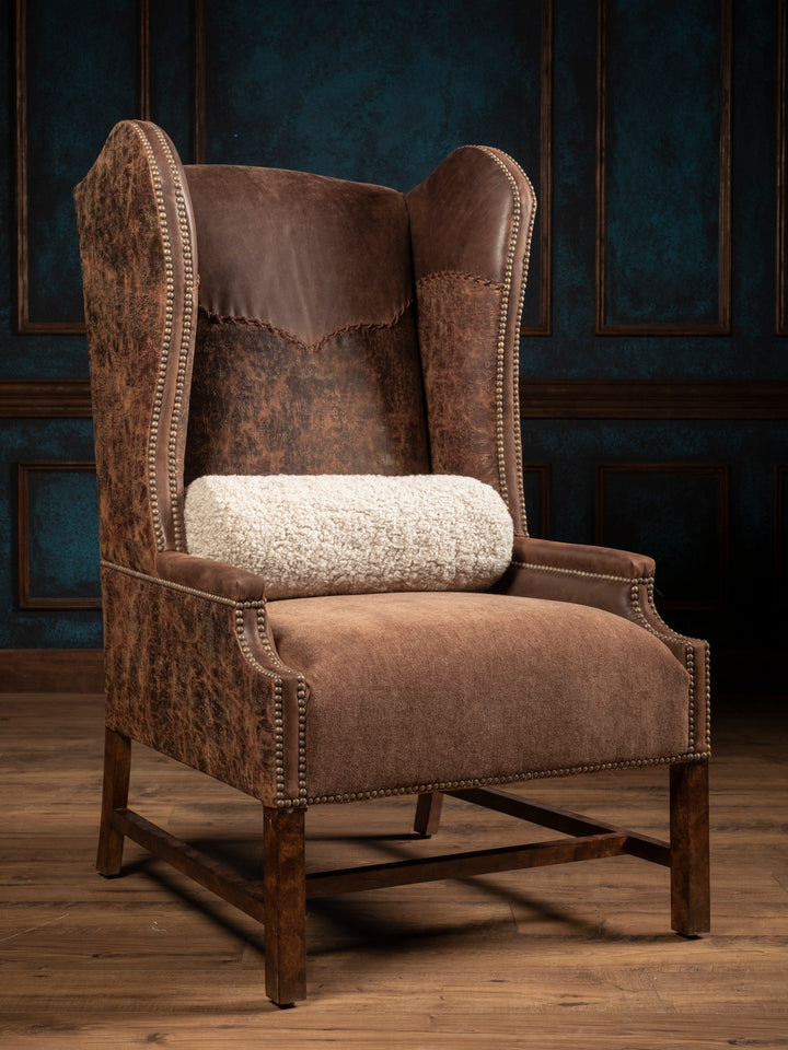 Stockman Western leather and velvet wingback chair with a cream bolster pillow, nailhead trim and wood legs