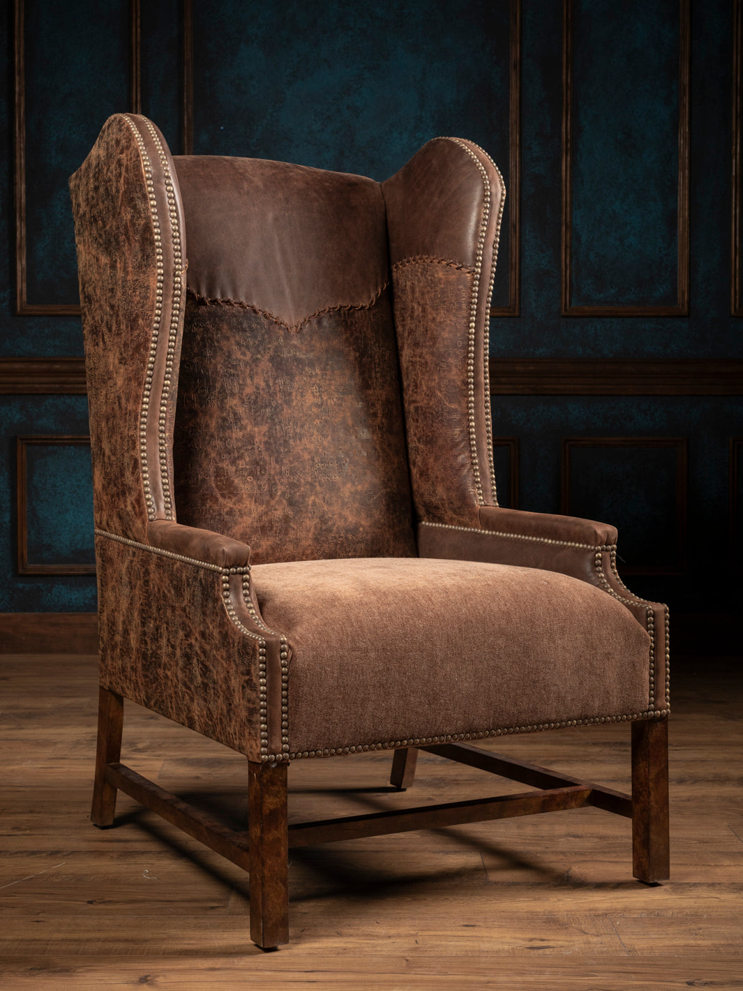 Stockman Western leather wingback chair with brown embossed leather, a velvet seat and yoke design in rustic room space.