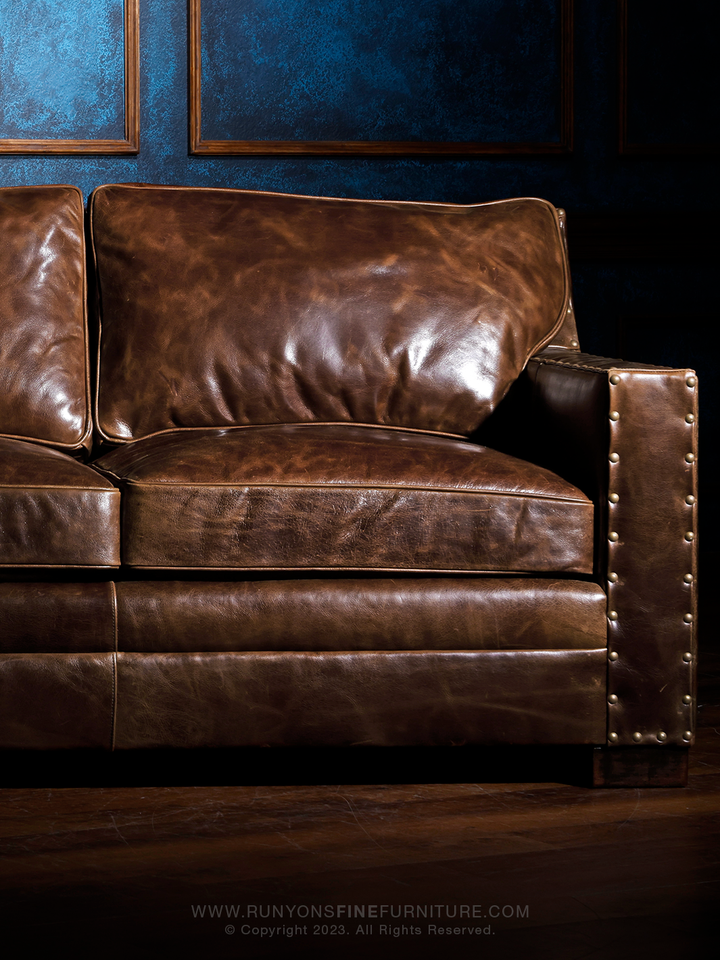 Tennessee Whiskey Brown Leather Sofa in distressed Mahogany Buffalo Leather with oversized brass nailheads and square feet in a moody rustic living room. 