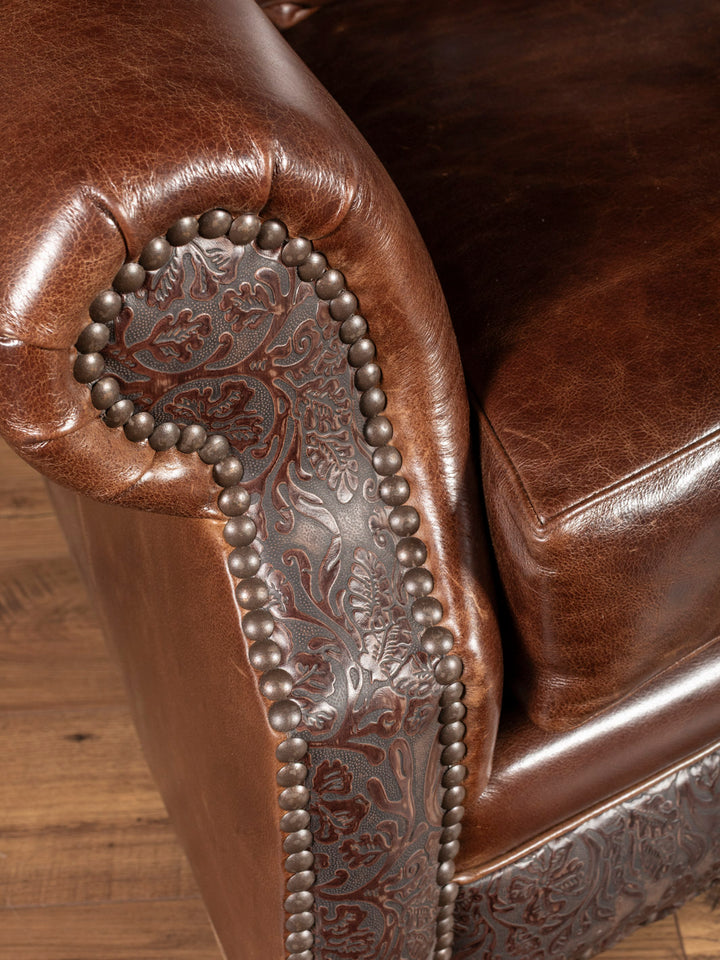 Texas Luxe Leather Curved Sofa in Dark Rum leather and embossed leather accents with brass nailhead trim in a close up view.