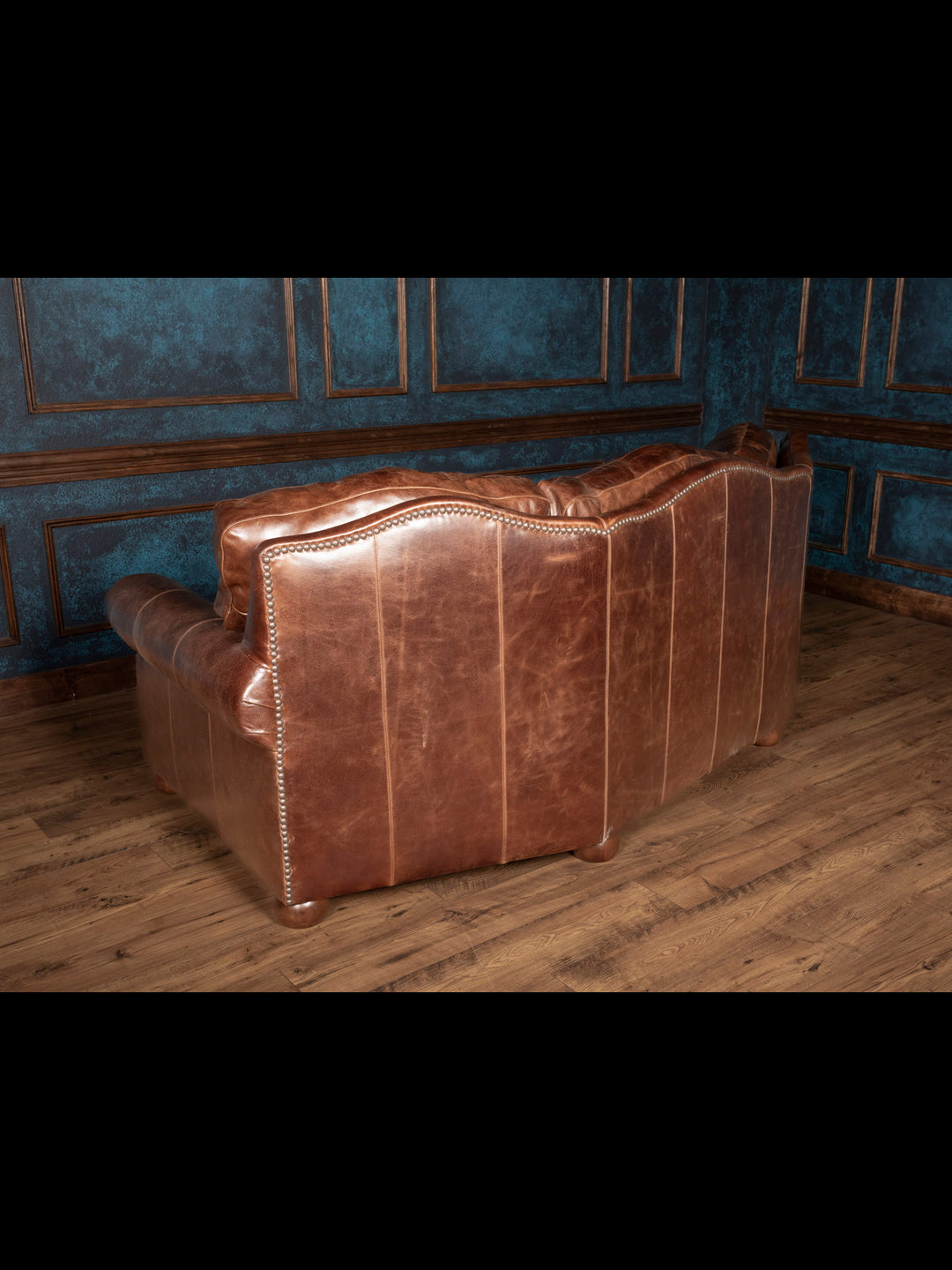 Texas Luxe Leather Curved Sofa with durable buffalo leather and nailhead trim on outside back in a studio space.