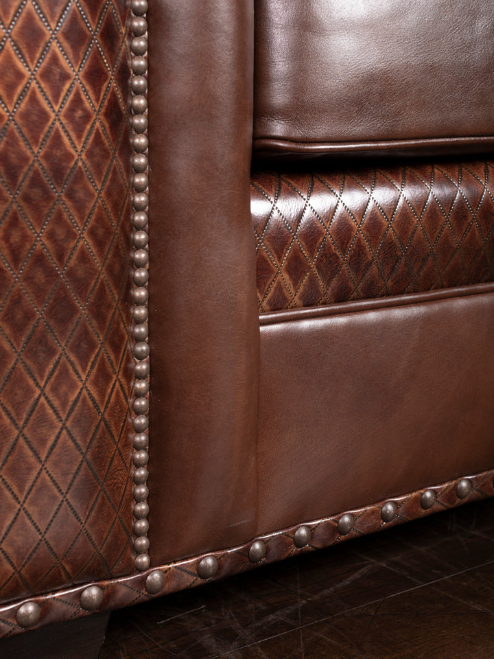 Tufted Cigar Lounge Leather Sofa in chestnut brown leather with diamond stitch accents and brass nailheads in a close up view. 