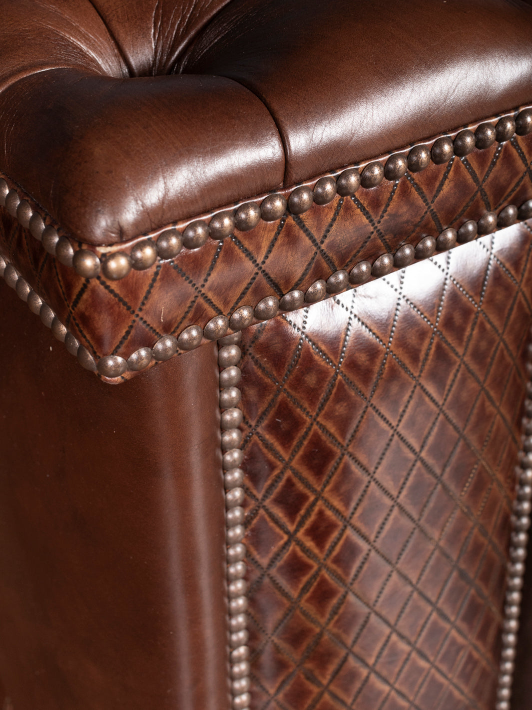 Tufted Cigar Lounge Leather Sofa with diamond stitch leather inlay and brass nailhead trim in a close-up view.