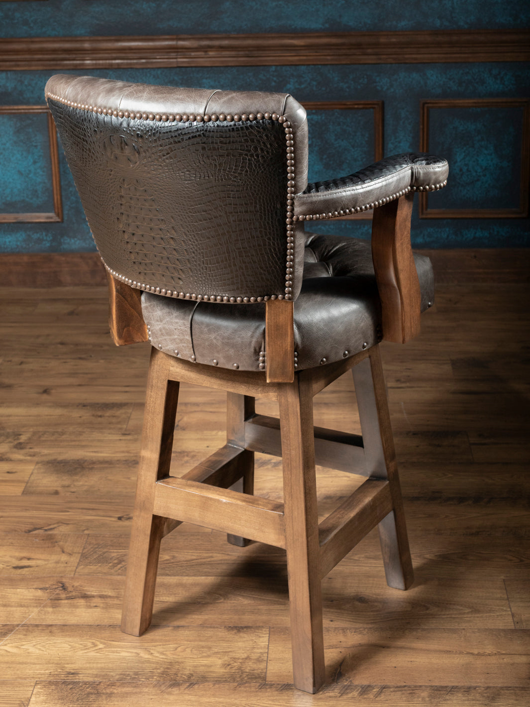 Tufted Greystone Leather Bar Stool with embossed crocodile accents and brass nailheads in a rustic room space.