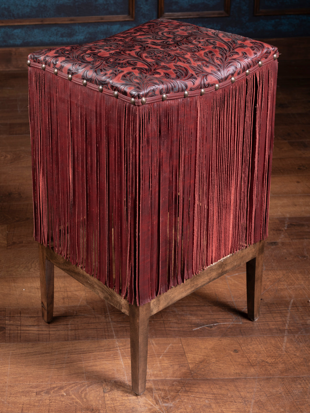 Product image showcasing red and black embossed seat and red fringe detailing. 