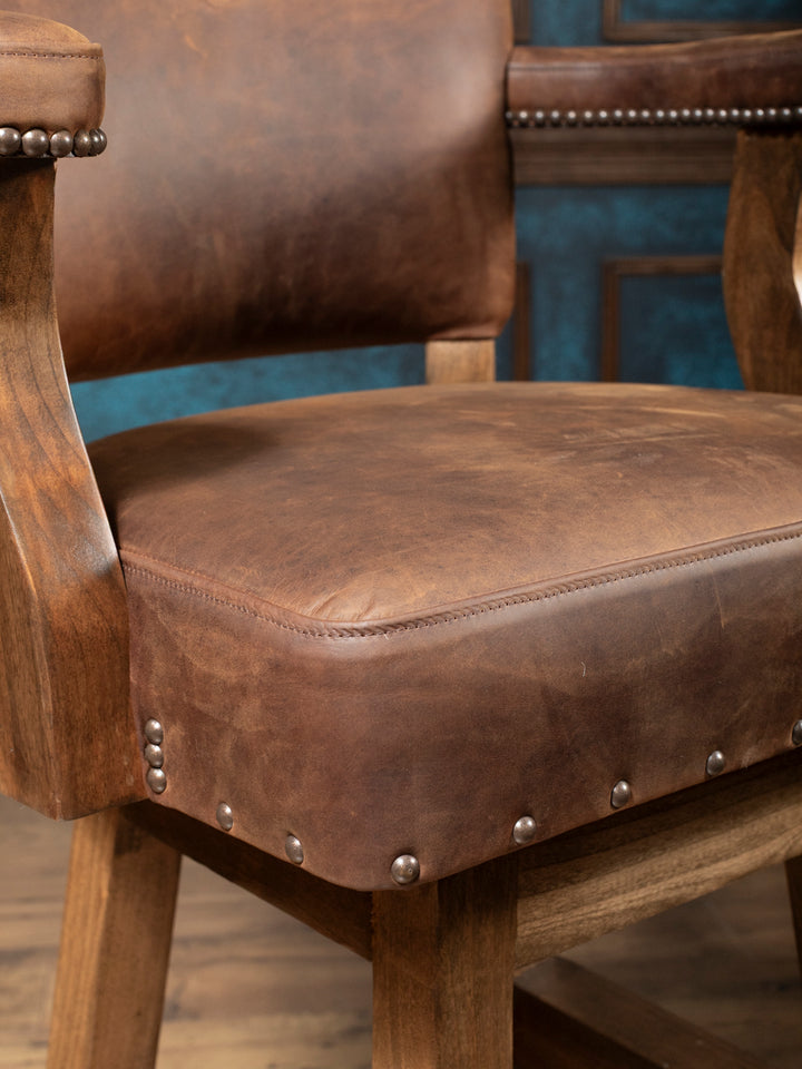Western Heritage Leather Barstool in distressed leather with brass nailheads and walnut hardwood frame in a close-up view.