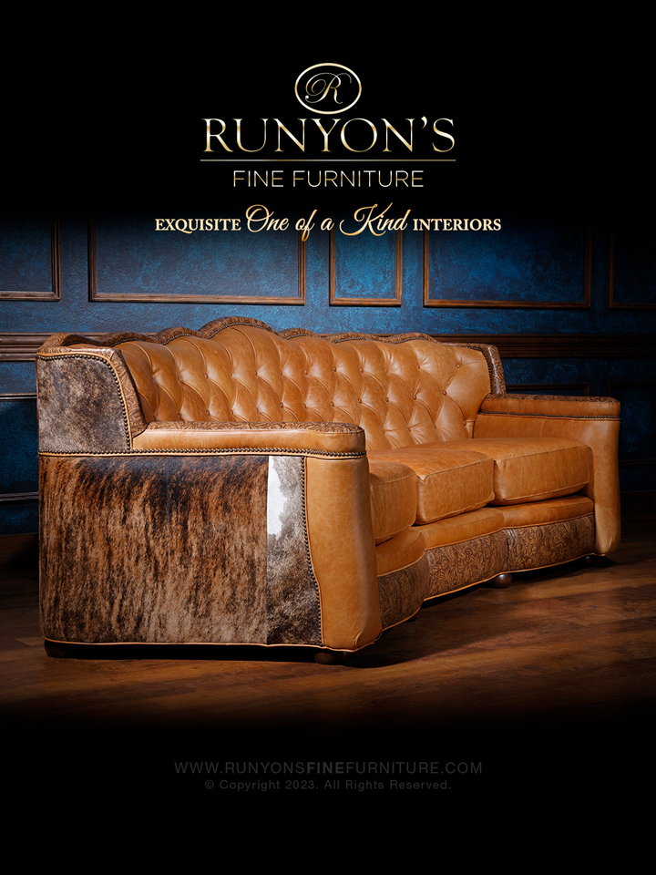 Western Heritage Tan Leather Sofa in Sierra Tan leather with embossed floral trim and cowhide accents in a moody western setting.