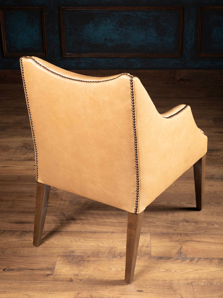 Rear view of the Ridgecut Western leather dining arm chair featuring sculptural lines, decorative nailhead trim, and solid hardwood legs.