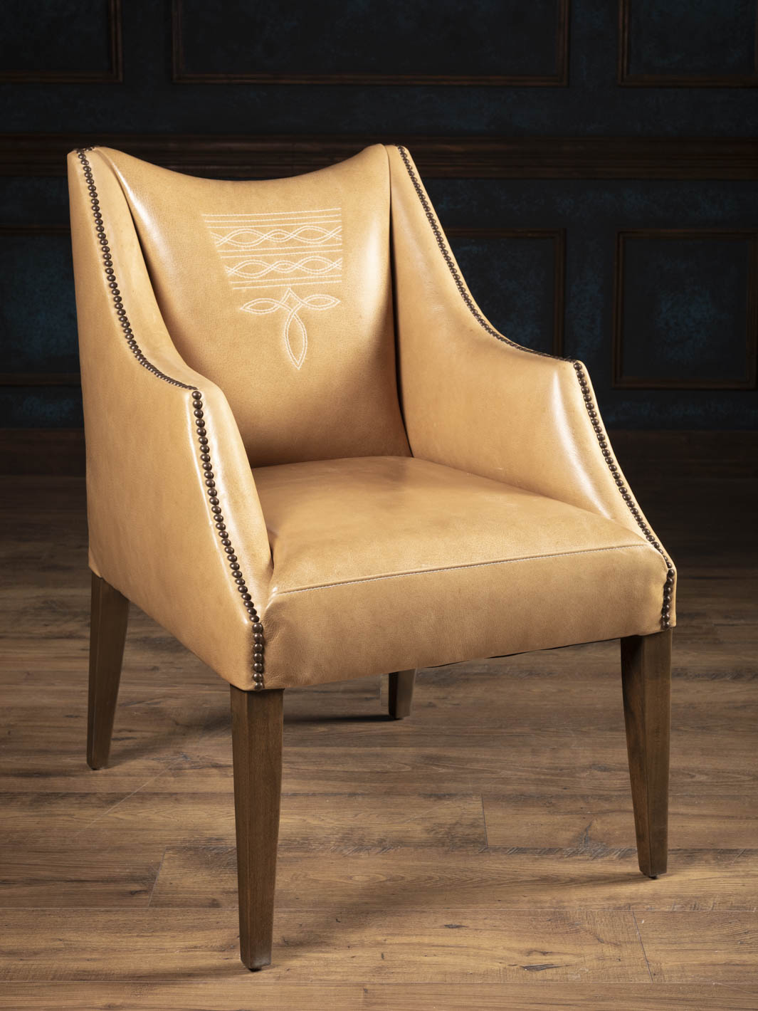 Western leather dining arm chair upholstered in premium full-grain buffalo leather with signature boot stitch detailing and sculptural dropped-arm silhouette.