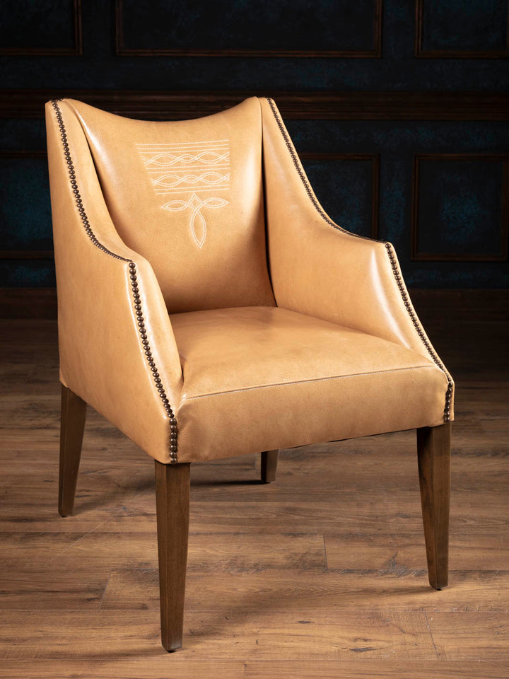 Western leather dining arm chair upholstered in premium full-grain buffalo leather with signature boot stitch detailing and sculptural dropped-arm silhouette.