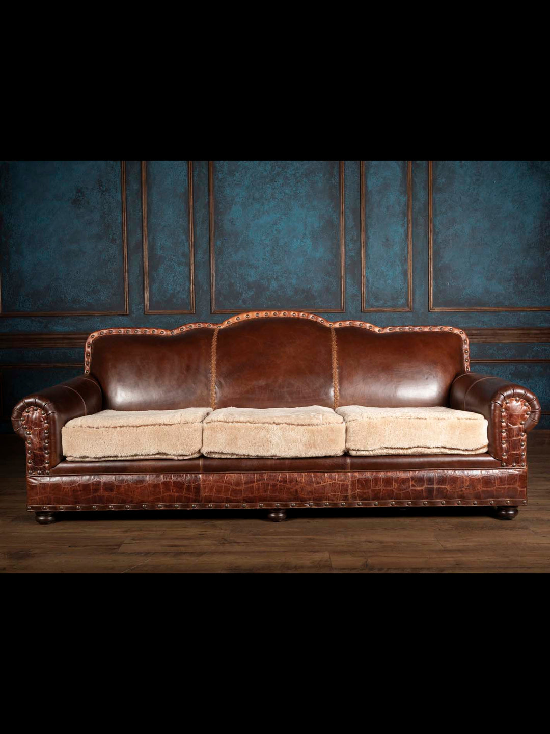 Straight-on front view of a three-seat Western rolled arm sofa with camel shearling cushions and hand-whipstitched back detailing.