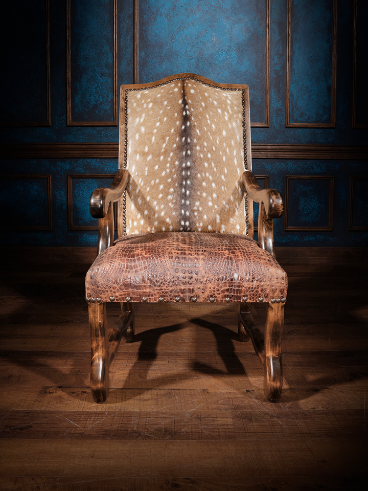 Front view of a wooden armchair featuring a backrest upholstered in embossed axis hide and a seat covered in crocodile-embossed leather, accented with nailhead trim.
