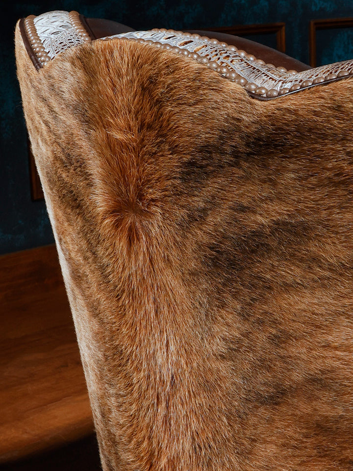 Close-up of a western-style swivel chair highlighting the hair-on-hide upholstery on the exterior, accented with crocodile-patterned leather trim and nailhead detailing.