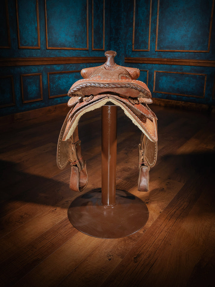 Rear view of a western-style saddle bar stool, showcasing the underside with plush fleece lining and durable stirrups, mounted on a metal base.