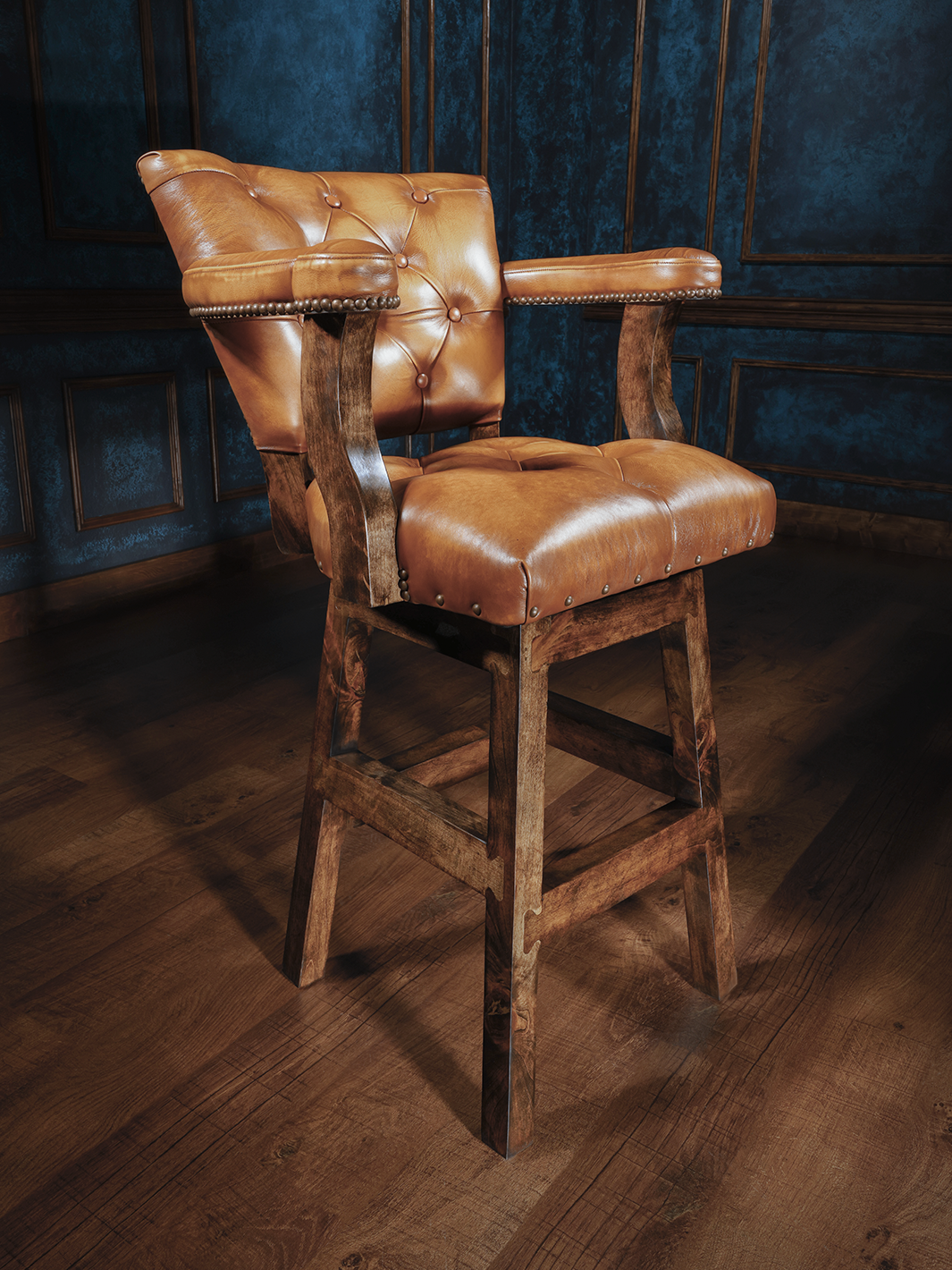A wooden barstool with a button-tufted leather seat and backrest, featuring armrests and nailhead trim, upholstered in rich tan leather