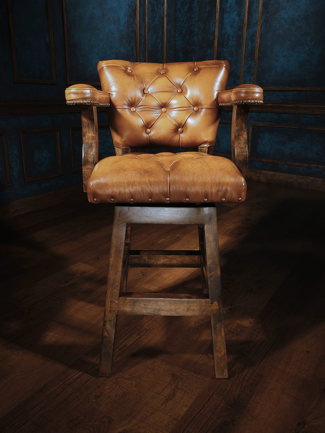 front view of wooden barstool with a button-tufted leather seat and backrest, featuring armrests and nailhead trim, upholstered in rich tan leather
