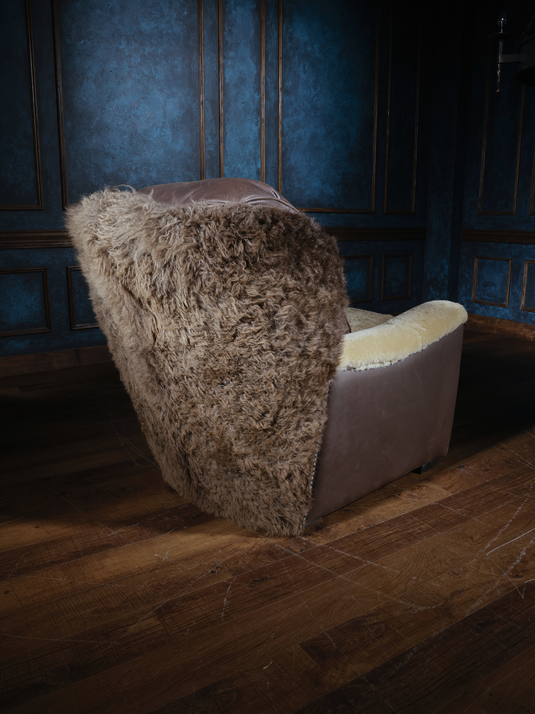 A Western-style leather accent chair featuring a back and arms covered in shearling, with a smooth leather seat cushion and leather accents on the sides.