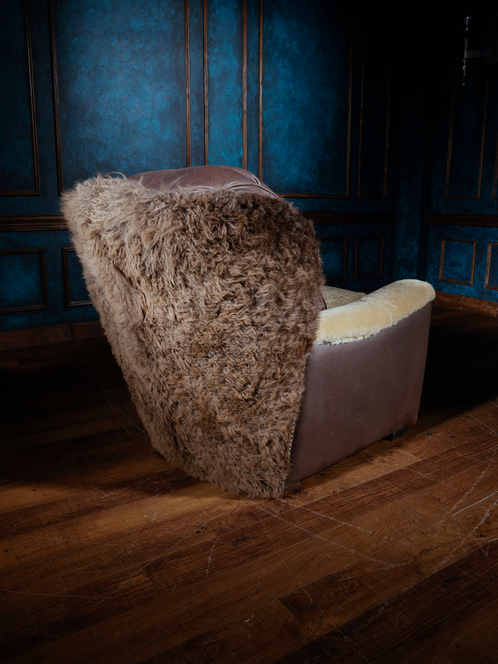 A Western-style leather accent chair featuring a back and arms covered in shearling, with a smooth leather seat cushion and leather accents on the sides.