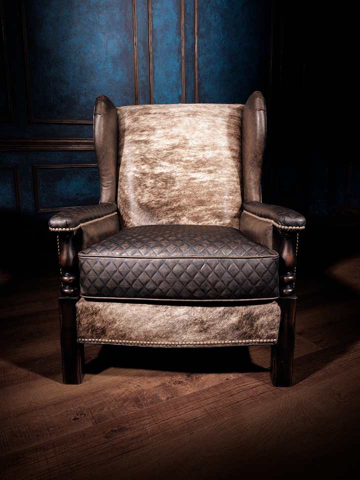Front view of a chair featuring a hair-on-hide backrest, quilted leather seat, leather arms, and nailhead trim, with a wooden frame.